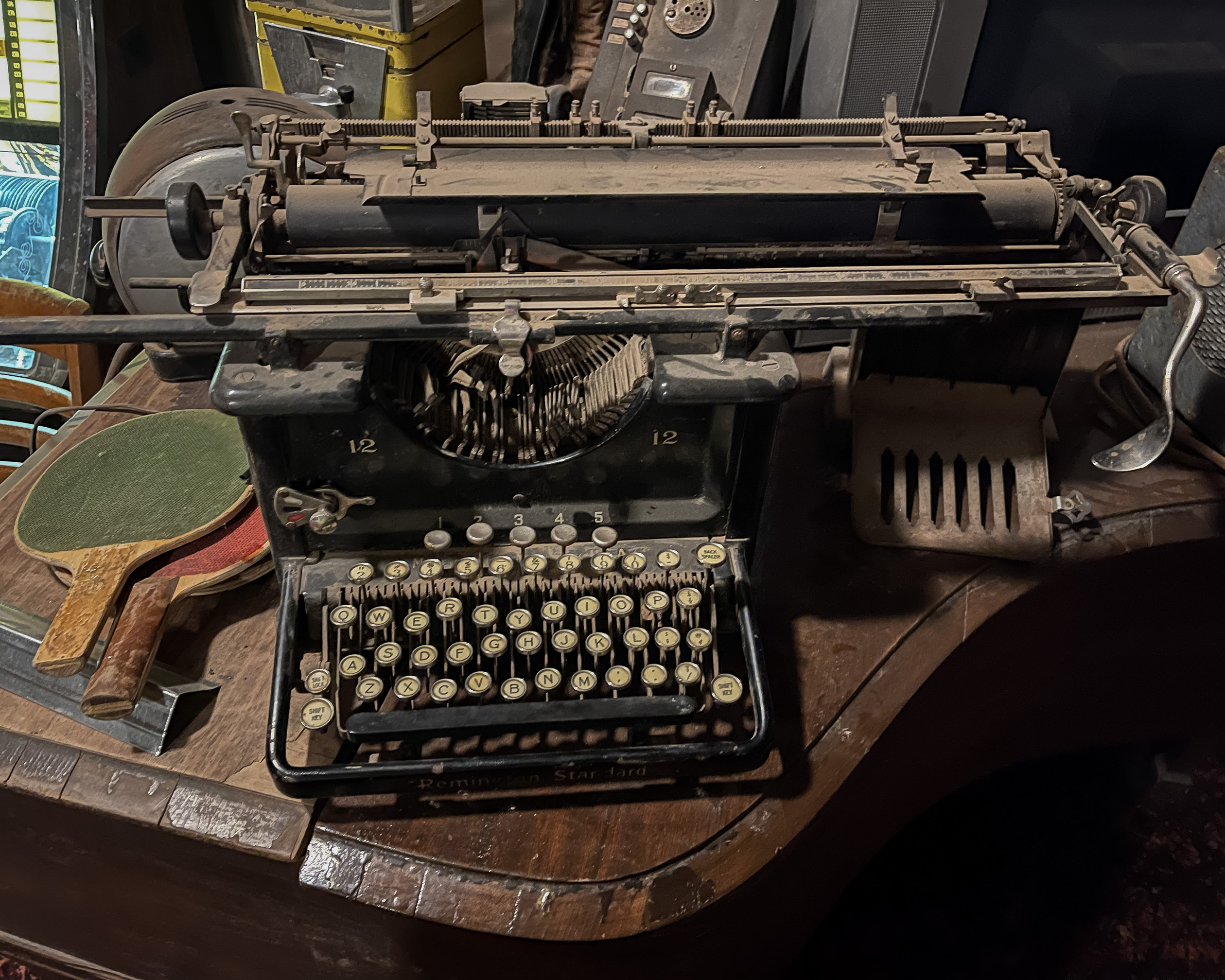 Typewriter A worn manual typewriter with round keys among old objects on a wooden table.
